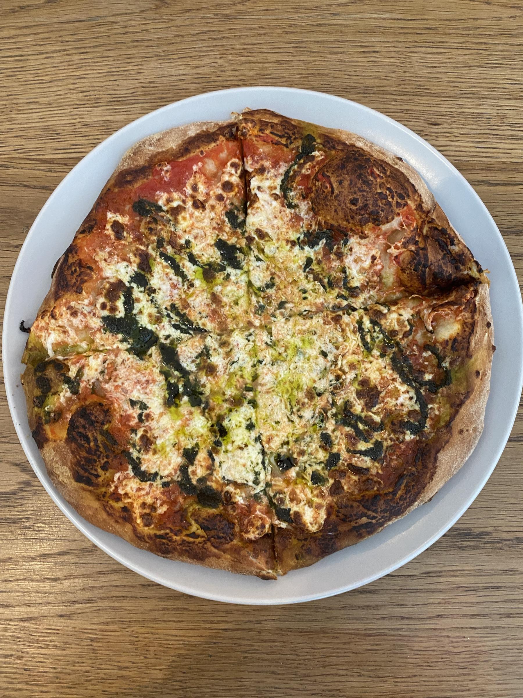 Wood-fired margherita pizza on a white plate.