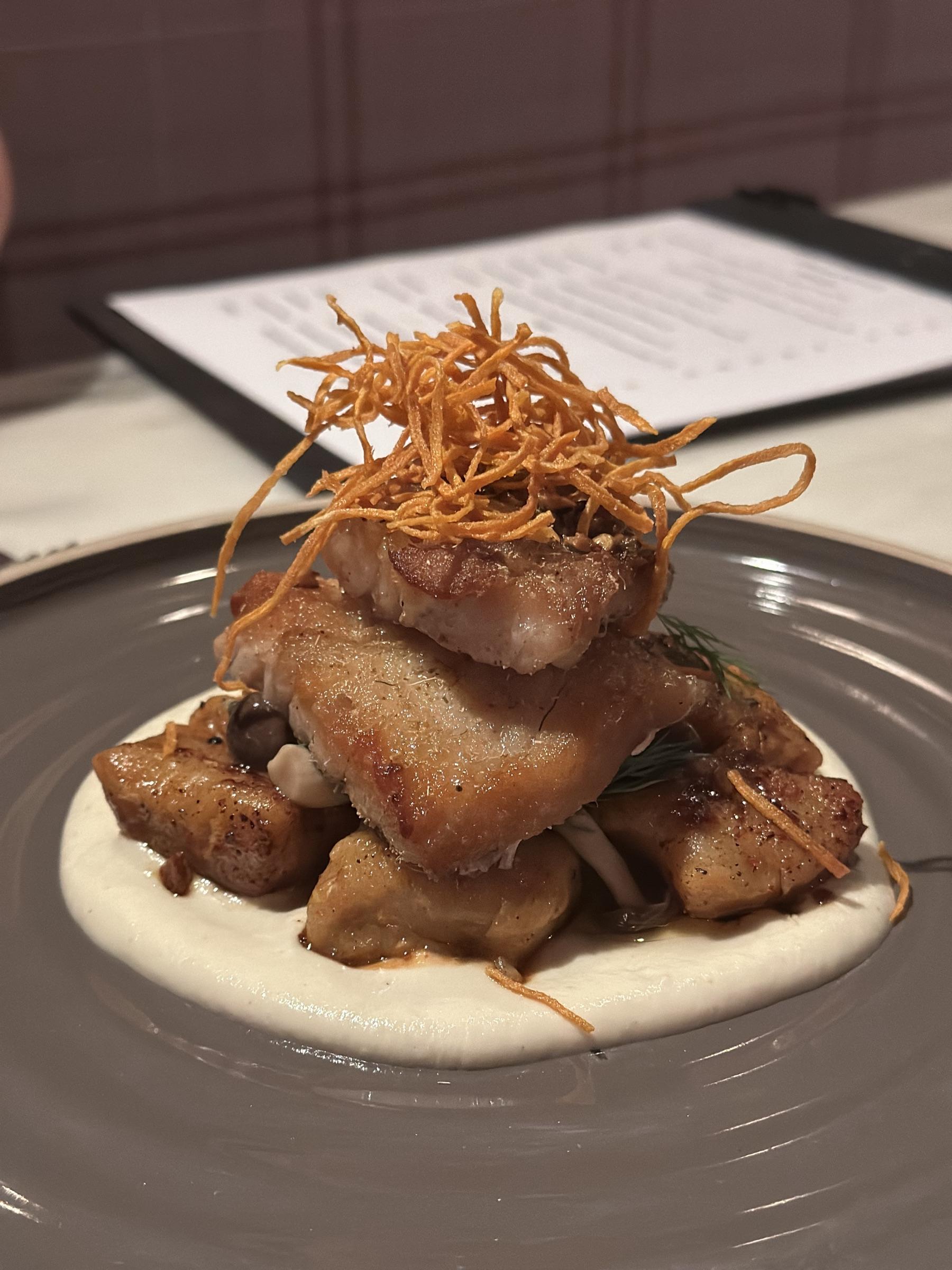 Plated pork belly on a swirl of cauliflower puree.