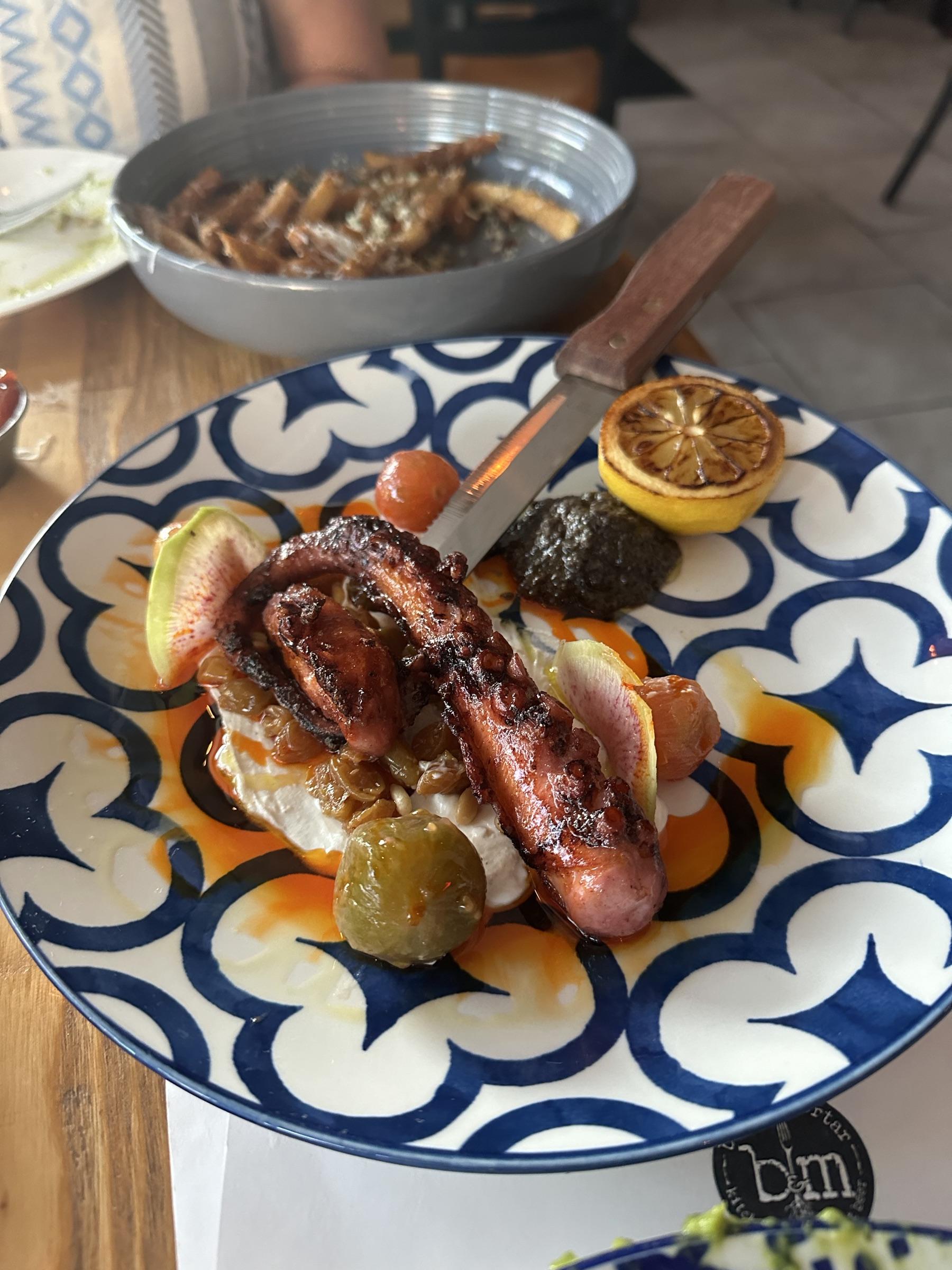 Charred octopus over labneh on a Mediterranean tile plate.